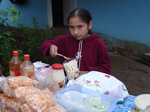 Little girl adding chile to popcorn.