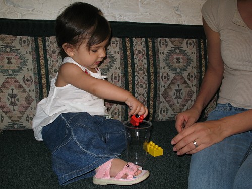 Alice playing block in the cup: first Duplo brick goes in.