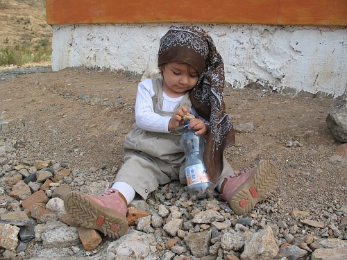 Alice trying to put a too large stone in an empty water bottle.