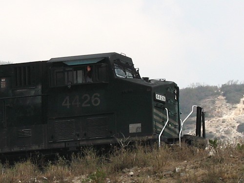 Close-up of the train. Train driver waving at Alice.