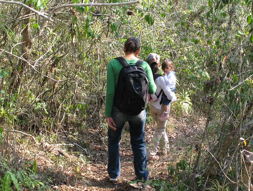 Rocio, and Esme carrying Alice, following a track down into the canyon.