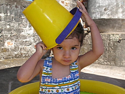 Alice playing with a plastic bucket on the roof.